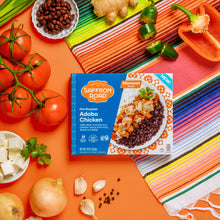 Load image into Gallery viewer, Fire-Roasted Adobo Chicken with Black Beans &amp; Rice Frozen Dinner Package on bright background with vegetables
