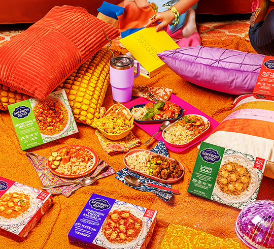 Snacks and food packages on a colorful blanket with people in the background