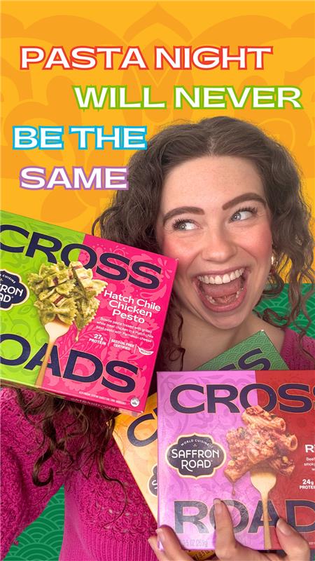 Person holding Cross Roads pasta packages with promotional text on a colorful background